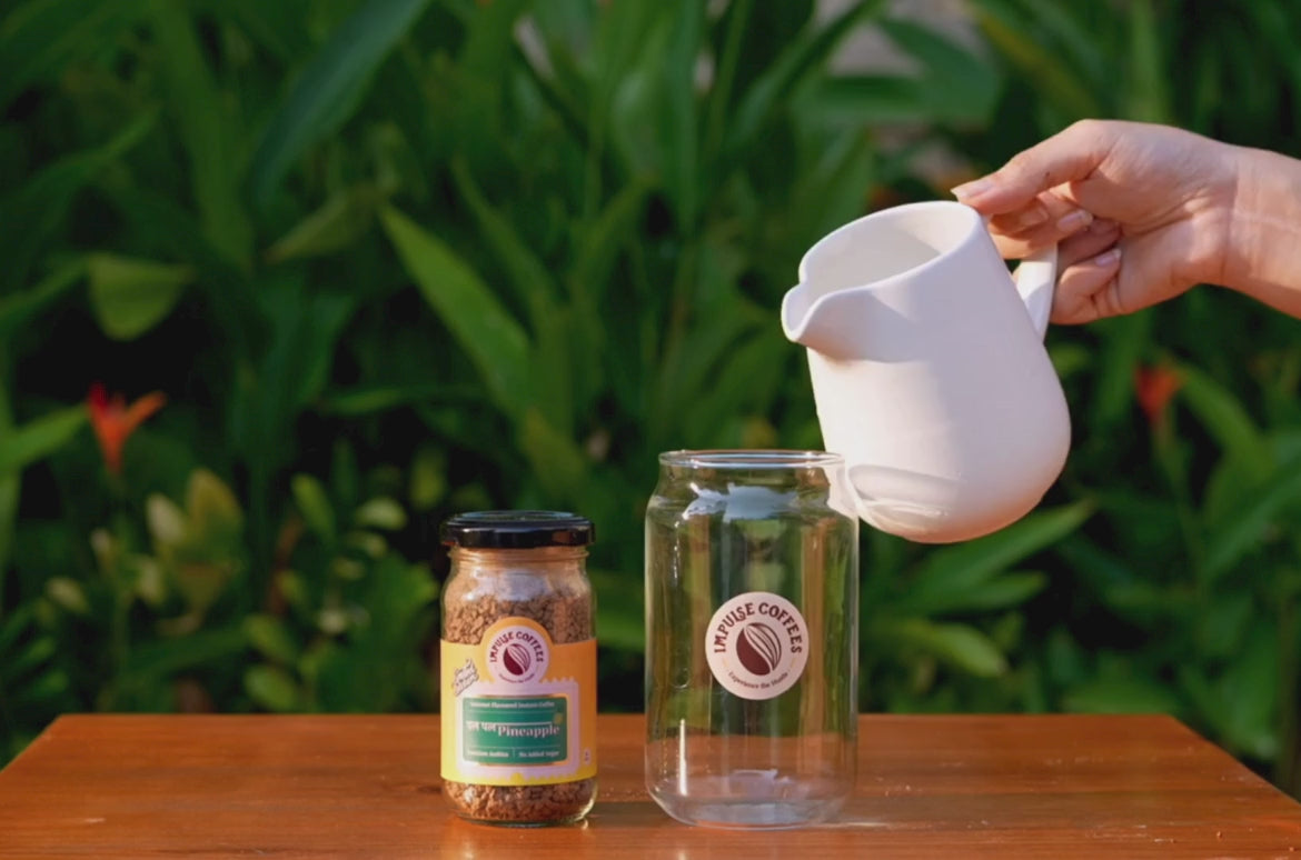 A video of pouring water in a Jar of Impulse Coffees and then adding 1 tsp of Pal Pal Pineapple Coffee to it, the background seems to be greenery and from the left it seems like a sunset.