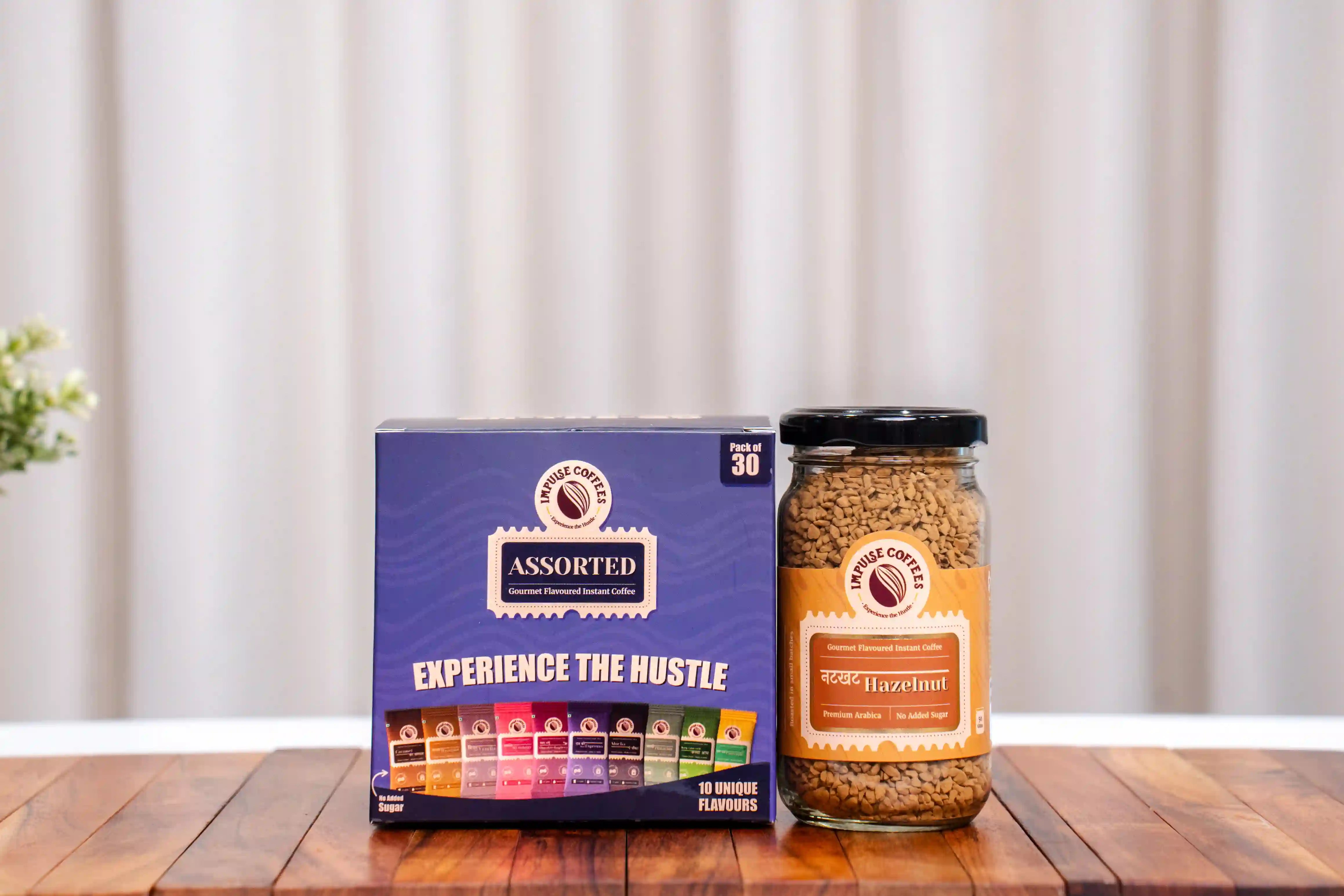 Assorted coffee pack of 30 sachets and Nutkhat Hazelnut Coffee 50gms packaging on a wooden surface with a neutral background