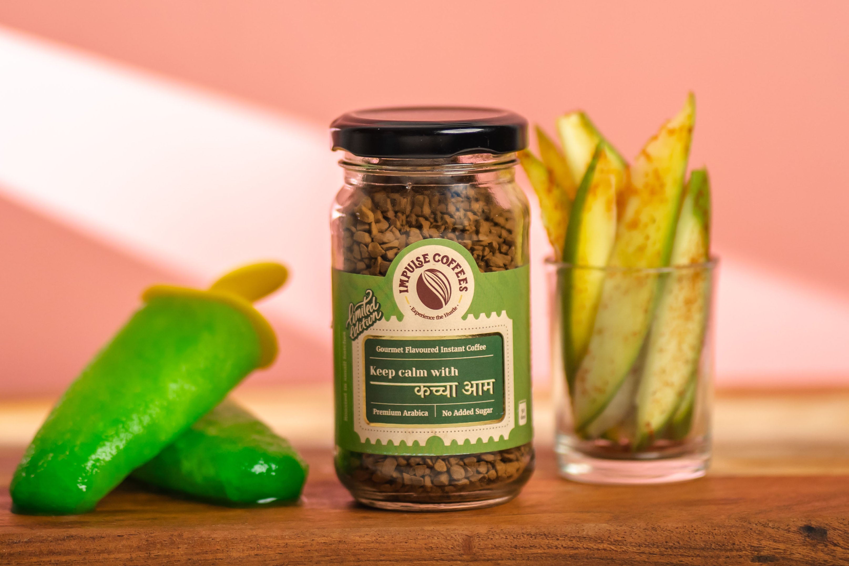 KACCHA AAM Premium Instant Coffee by Impulse Coffees, alongside kaccha aam cut into pieces and kept in a glass and 2 pieces of kaccha aam