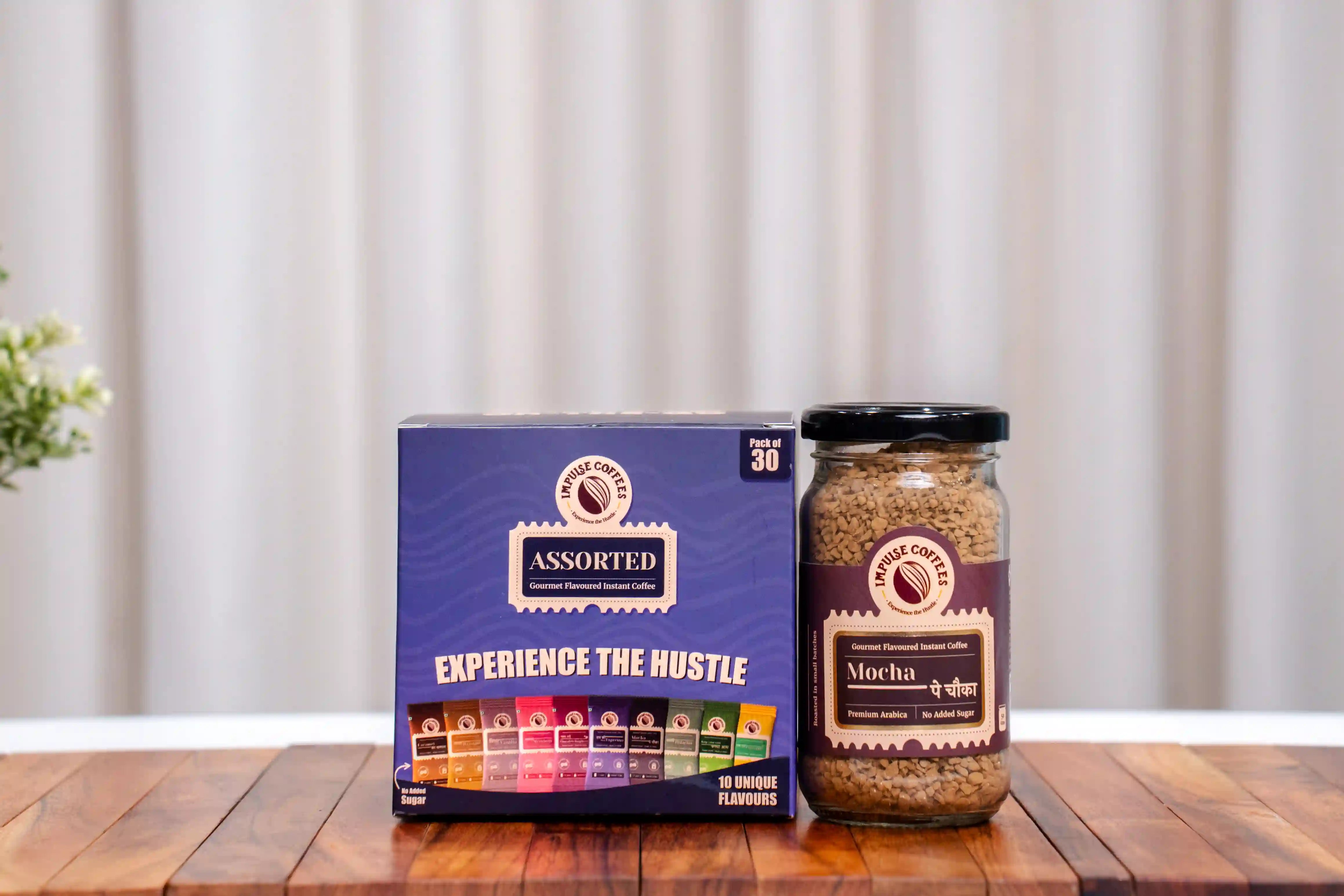 Assorted coffee pack of 30 sachets and Mocha Pe Chauka coffee 50gmspackaging on a wooden surface with a neutral background