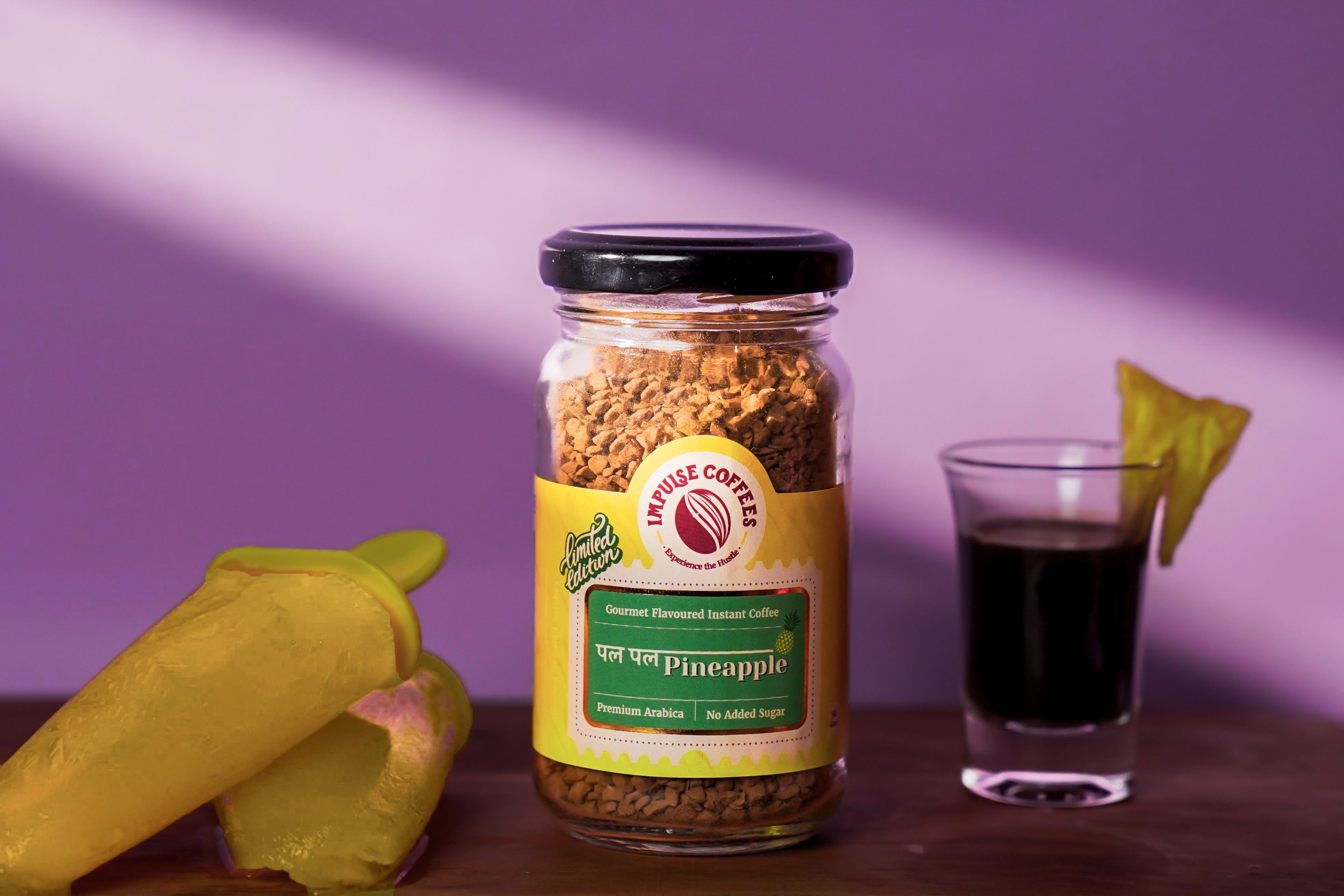 Pal Pal Pineapple 50 gms Premium Instant Coffee Jar by Impulse Coffees alongside a pineapple shorts and real pineapple