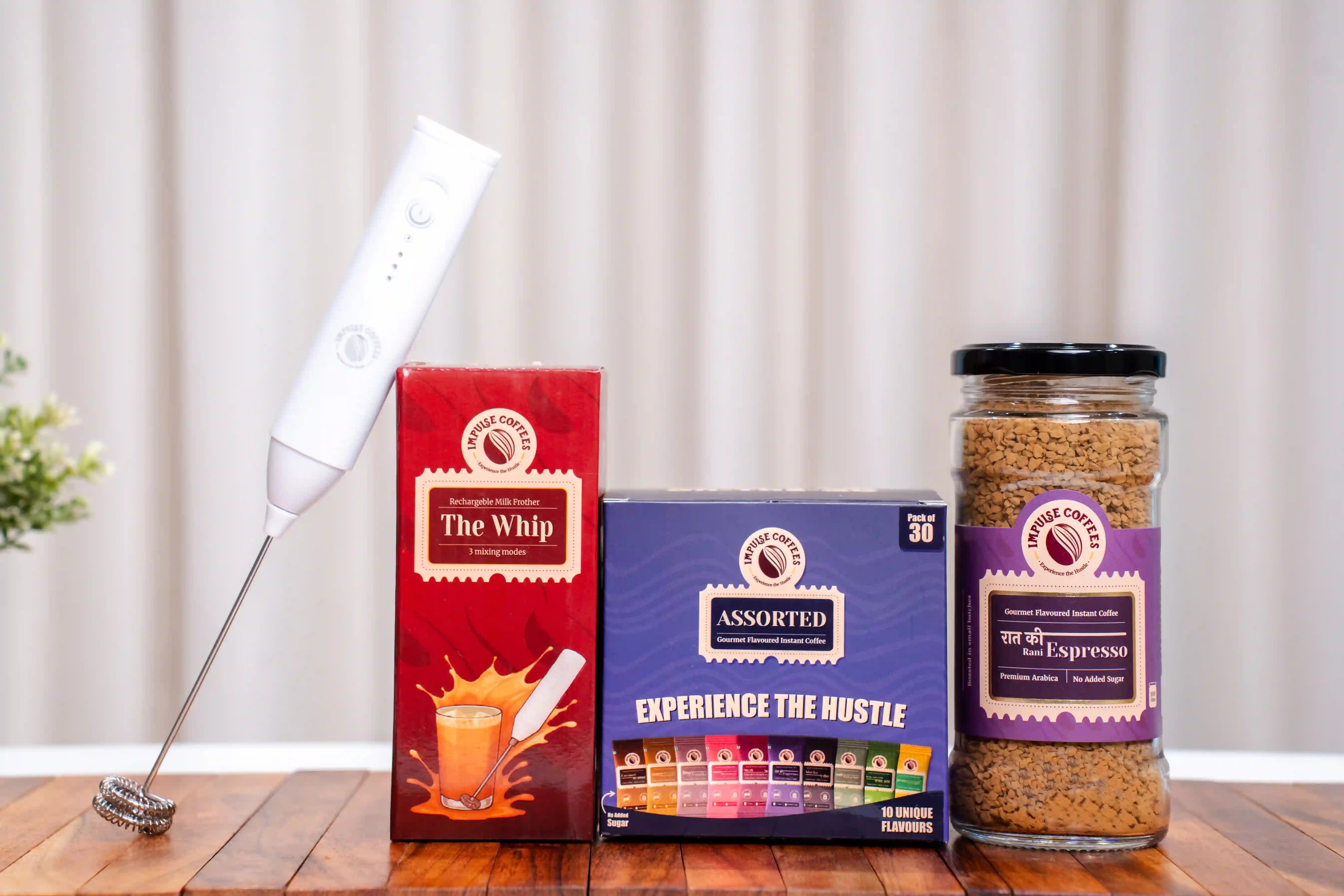 Assorted coffee sachets including a milk frother, coffee boxes, and a jar of espresso coffee on a wooden surface.